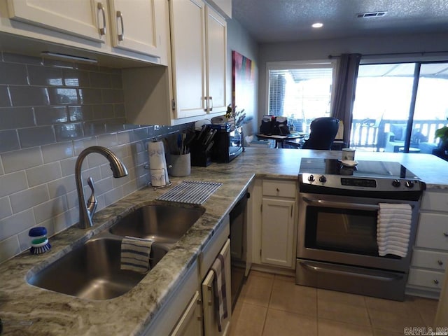 kitchen with light tile patterned floors, visible vents, decorative backsplash, a sink, and stainless steel electric range