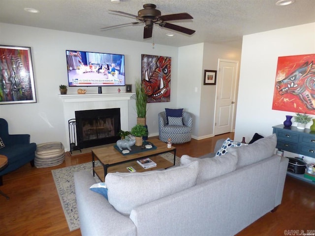 living room featuring a textured ceiling, recessed lighting, dark wood-style flooring, a ceiling fan, and a tiled fireplace