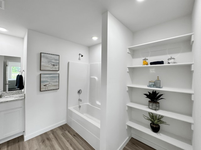 full bath with visible vents, baseboards, shower / bathtub combination, wood finished floors, and vanity