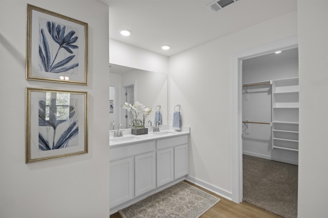 bathroom with double vanity, a spacious closet, visible vents, and a sink