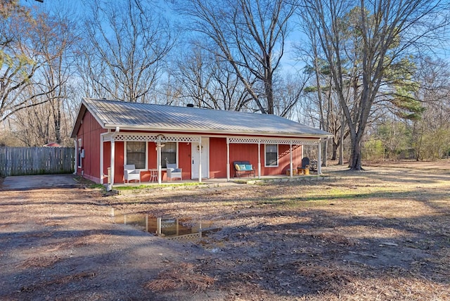 view of front of house featuring metal roof, a porch, and fence