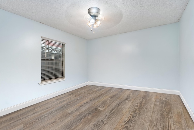 spare room with a textured ceiling, wood finished floors, a ceiling fan, and baseboards