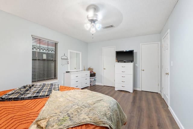 bedroom with a textured ceiling, dark wood-type flooring, visible vents, and baseboards