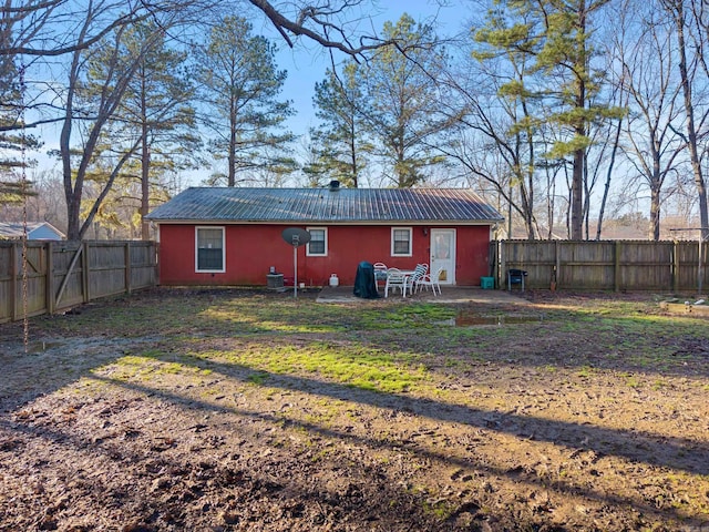 rear view of house featuring a fenced backyard, metal roof, a lawn, and a patio