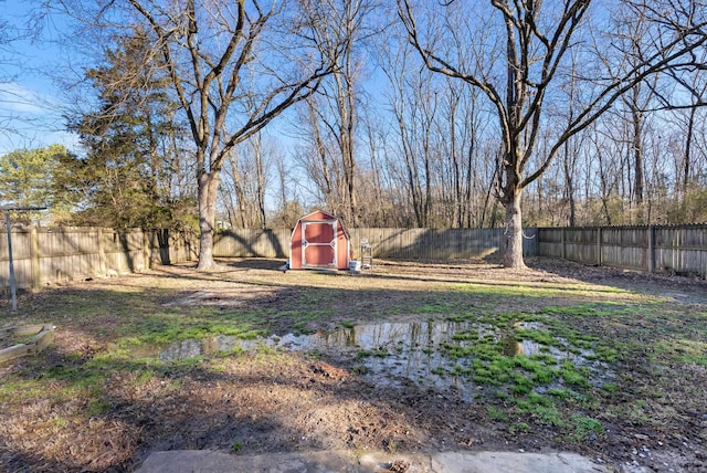 view of yard with a storage shed, a fenced backyard, and an outbuilding