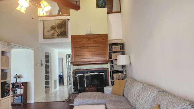 living area featuring a high ceiling, a fireplace, and wood finished floors