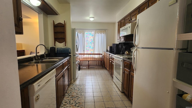 kitchen featuring dark countertops, white appliances, light tile patterned flooring, and a sink