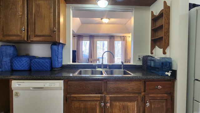 kitchen with dark countertops, dishwasher, a sink, and open shelves