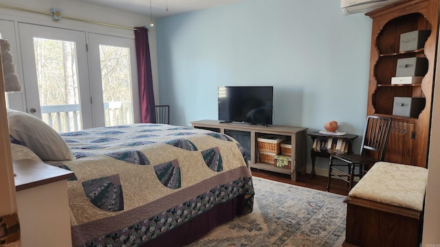 bedroom featuring access to exterior, wood finished floors, and a wall mounted AC