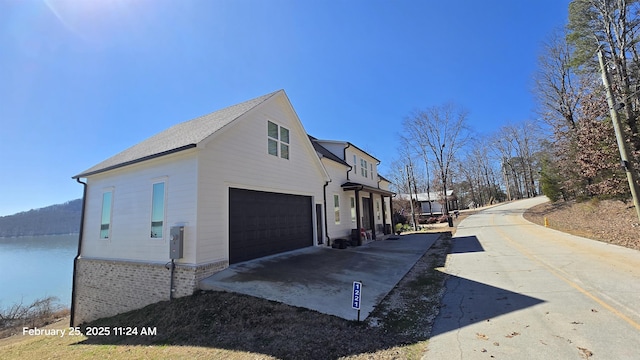 view of property exterior with a garage, driveway, and a water view