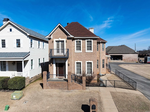 view of front of property featuring roof with shingles, brick siding, a chimney, and fence