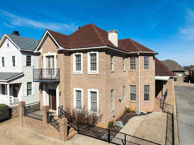 view of front of house with a fenced front yard, a shingled roof, and brick siding