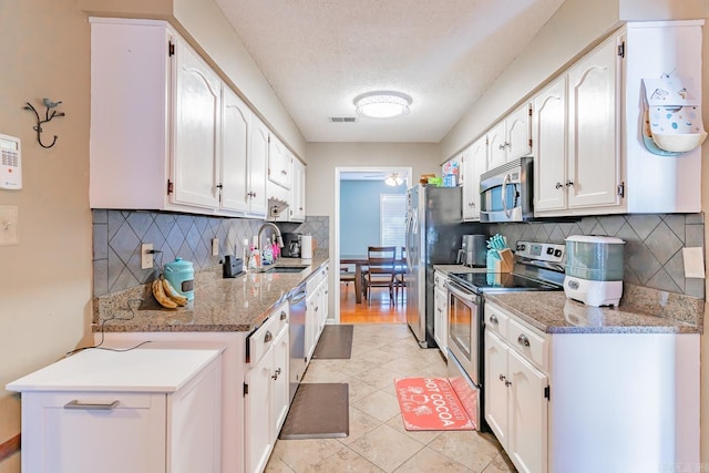 kitchen featuring light stone counters, a sink, visible vents, white cabinets, and appliances with stainless steel finishes