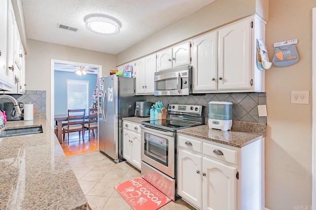 kitchen featuring visible vents, white cabinets, appliances with stainless steel finishes, light stone countertops, and a sink