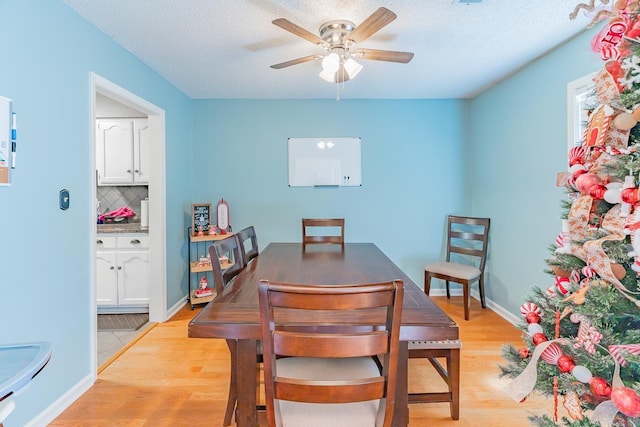 dining space featuring ceiling fan, light wood finished floors, and baseboards