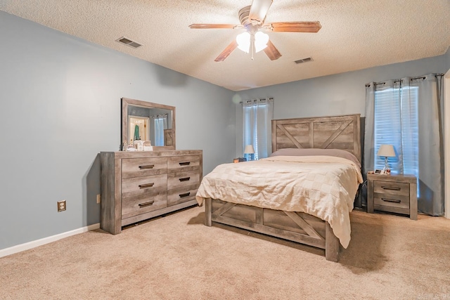 bedroom featuring light colored carpet, visible vents, a textured ceiling, and baseboards