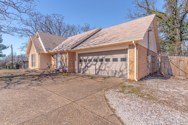 view of front of house featuring brick siding, fence, driveway, and an attached garage