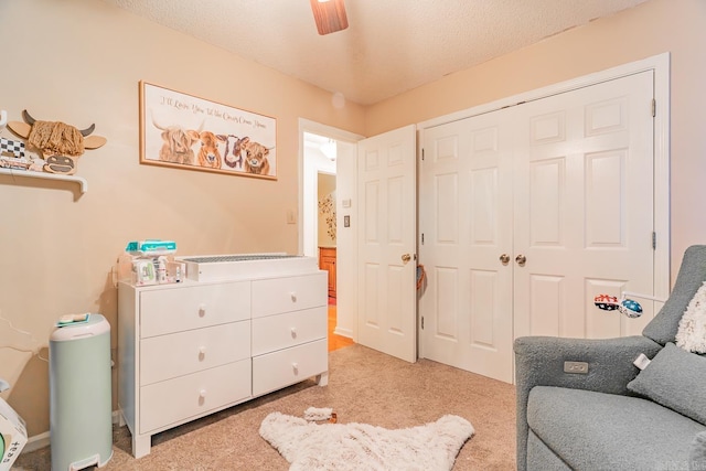 sitting room featuring light carpet, ceiling fan, and a textured ceiling