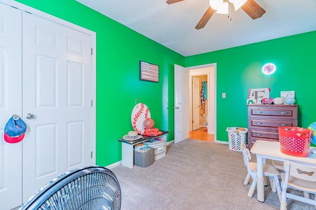 game room with light carpet, ceiling fan, a textured ceiling, and baseboards