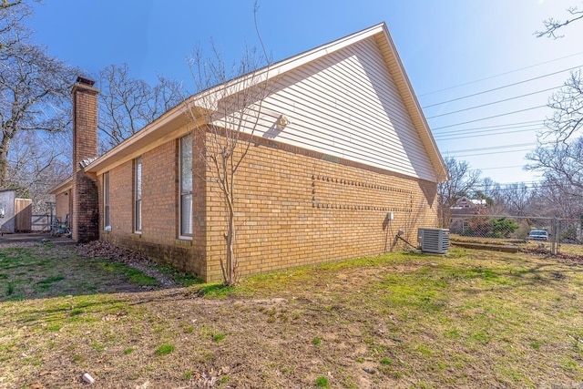 view of home's exterior featuring central AC unit, a chimney, fence, and brick siding