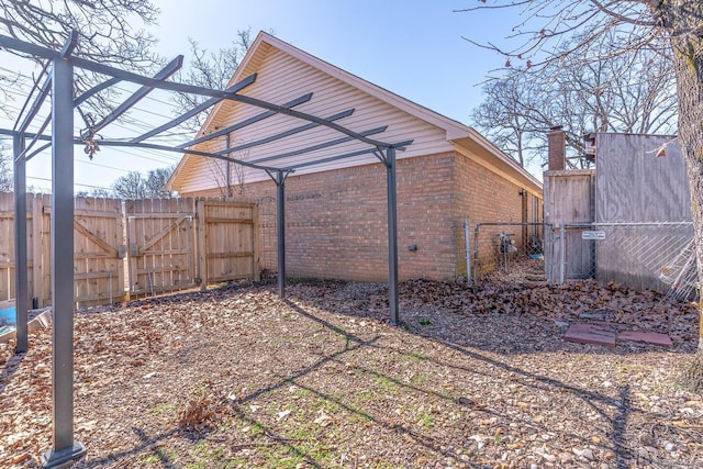 view of side of property featuring brick siding, fence, and a gate