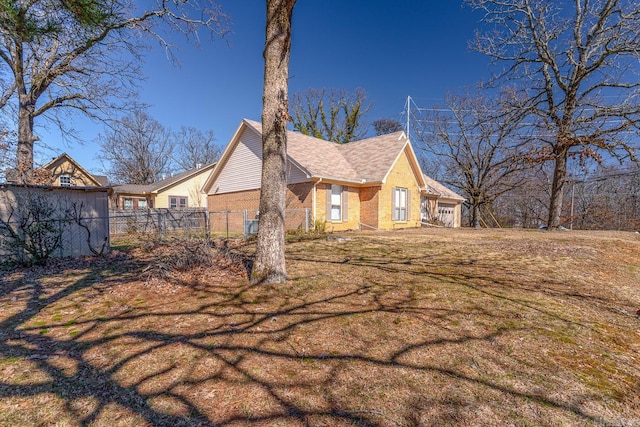 view of side of home featuring fence, a lawn, and brick siding