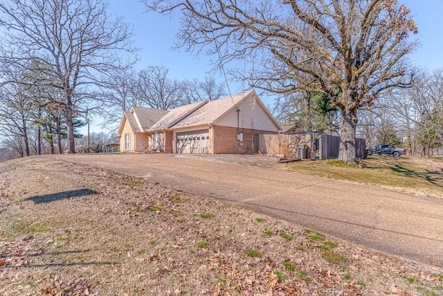 view of side of home with a garage, driveway, and brick siding