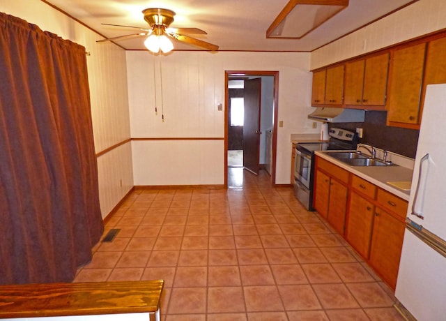 kitchen featuring under cabinet range hood, a sink, stainless steel range with electric cooktop, light countertops, and ornamental molding