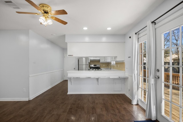 kitchen featuring white cabinets, a peninsula, stainless steel appliances, light countertops, and a sink