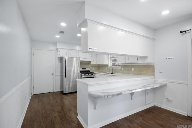 kitchen featuring stainless steel appliances, light countertops, white cabinetry, a sink, and a peninsula