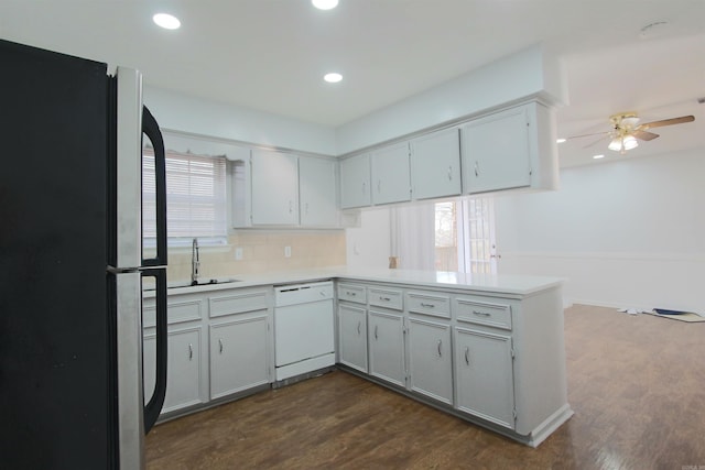 kitchen featuring dark wood finished floors, light countertops, freestanding refrigerator, a sink, and dishwasher