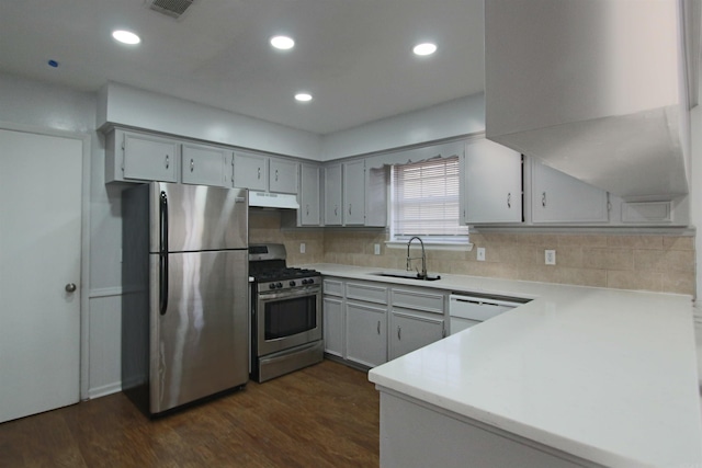 kitchen with appliances with stainless steel finishes, light countertops, a sink, and under cabinet range hood