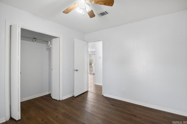 unfurnished bedroom featuring a ceiling fan, visible vents, baseboards, a closet, and dark wood finished floors