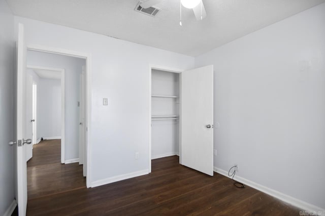 unfurnished bedroom featuring a closet, dark wood finished floors, visible vents, and baseboards