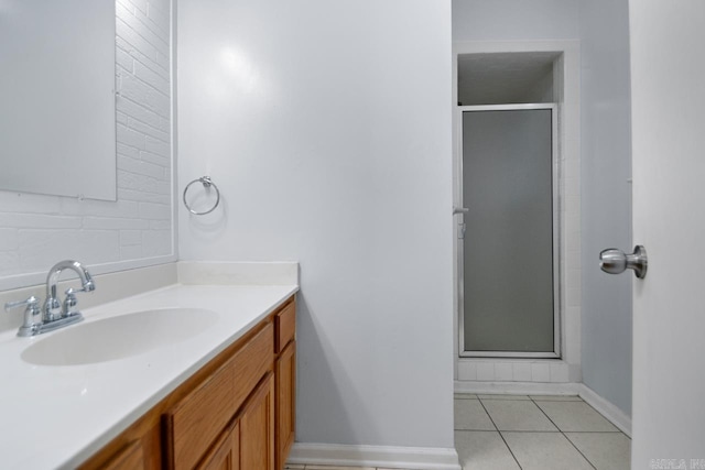 full bathroom featuring a stall shower, vanity, baseboards, and tile patterned floors