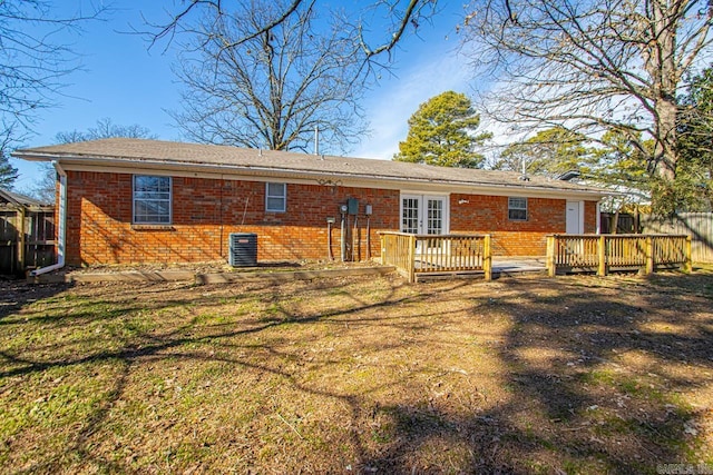 rear view of property featuring brick siding, french doors, a lawn, and a wooden deck