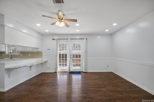 unfurnished dining area with french doors, dark wood-style flooring, a sink, and wainscoting