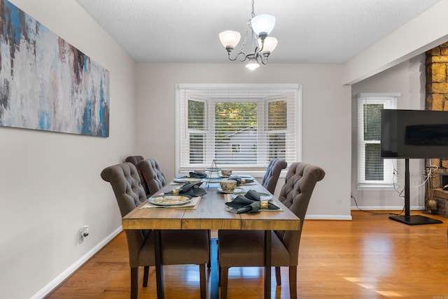 dining space with a notable chandelier, a textured ceiling, and wood finished floors