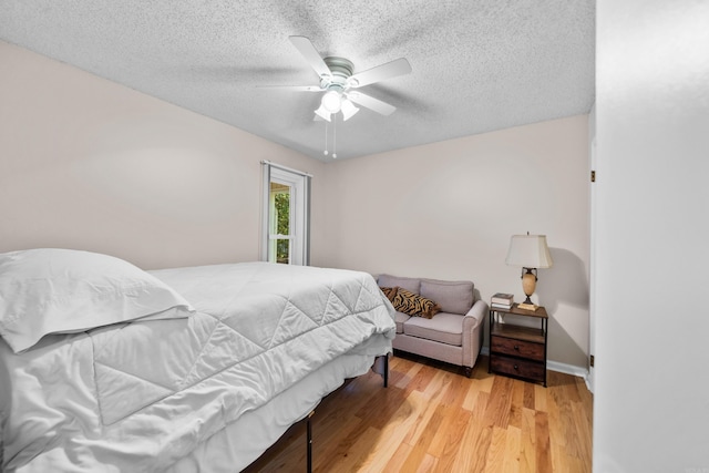 bedroom with a textured ceiling, light wood finished floors, and a ceiling fan