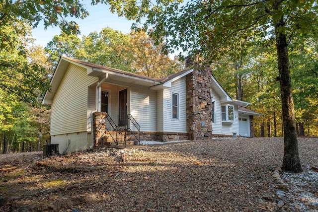 view of front of property featuring entry steps, central AC unit, and a chimney