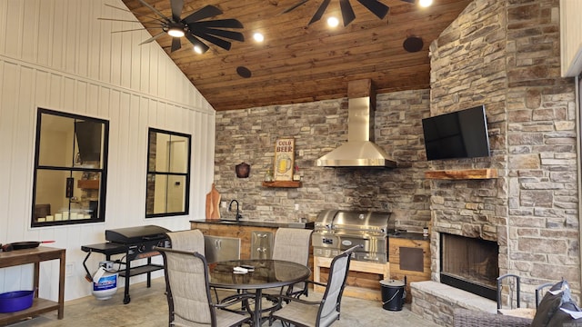 view of patio with an outdoor kitchen, a ceiling fan, a grill, a stone fireplace, and a sink