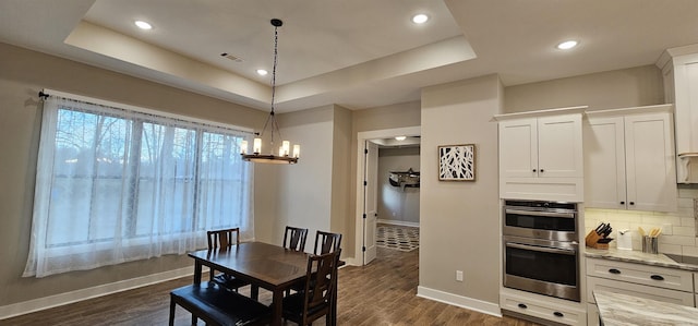 dining space with recessed lighting, visible vents, baseboards, dark wood-style floors, and a raised ceiling