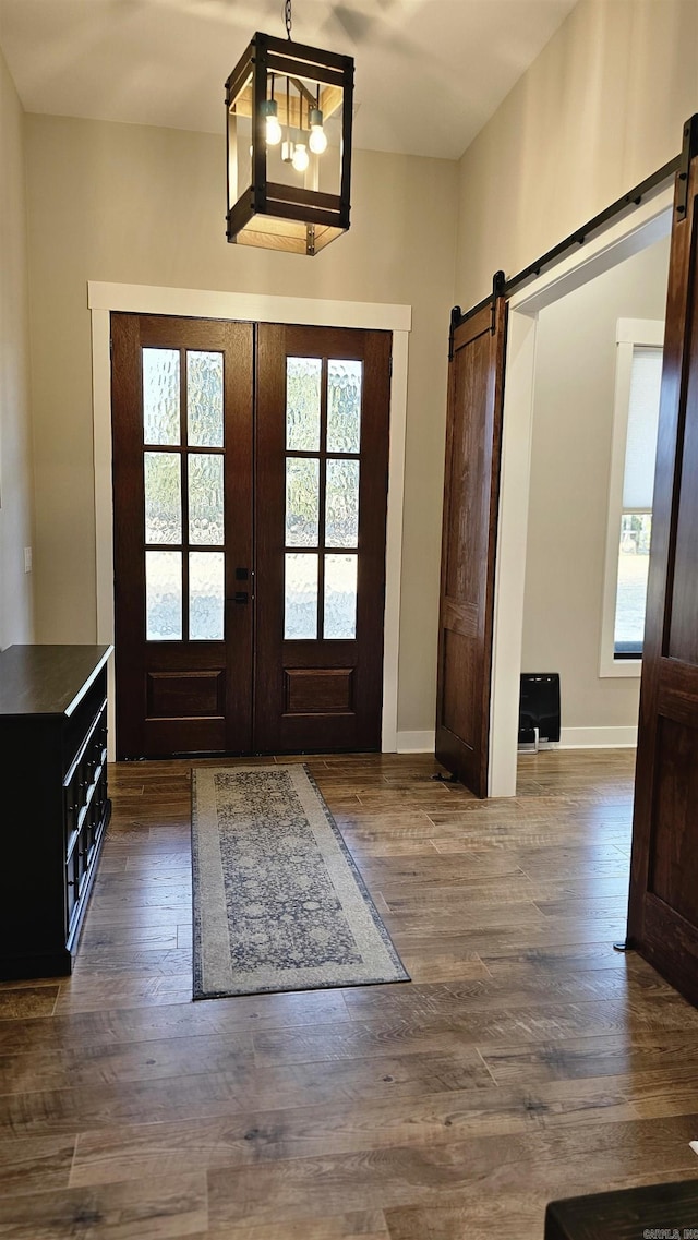 entryway featuring dark wood-style floors, french doors, and a barn door