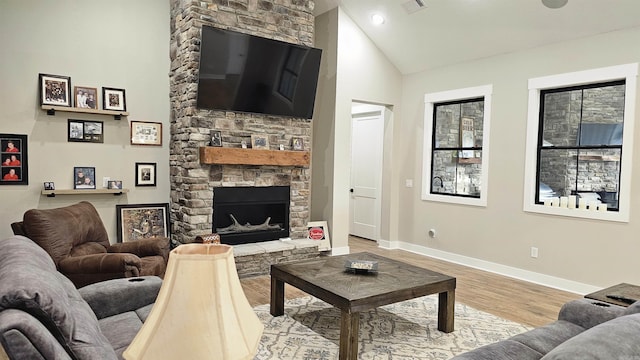 living area featuring a fireplace, visible vents, high vaulted ceiling, light wood-type flooring, and baseboards