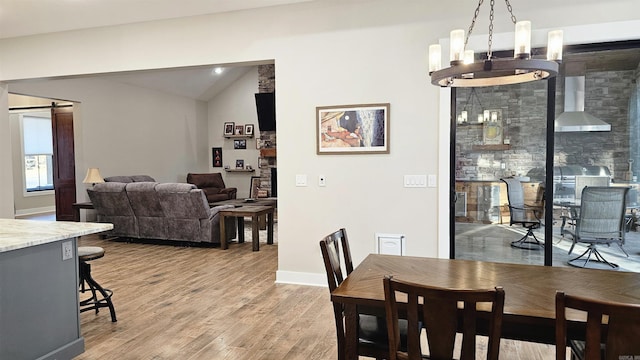 dining area featuring lofted ceiling, an inviting chandelier, a barn door, wood finished floors, and baseboards