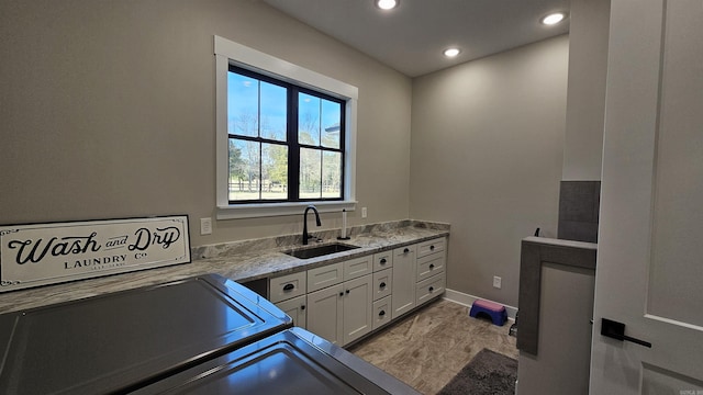 clothes washing area with cabinet space, baseboards, washing machine and clothes dryer, a sink, and recessed lighting