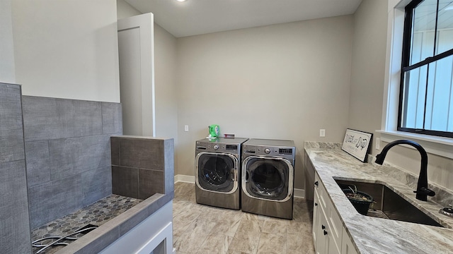 clothes washing area featuring washer and dryer, laundry area, a sink, and baseboards