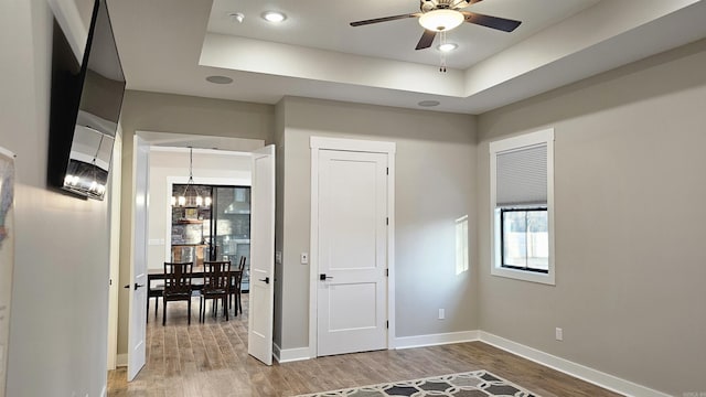 bedroom featuring a tray ceiling, an inviting chandelier, baseboards, and wood finished floors