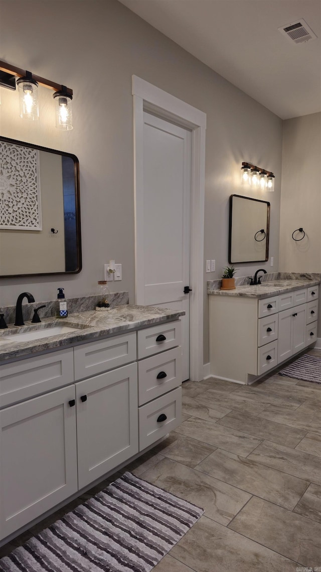 full bath with two vanities, a sink, and visible vents