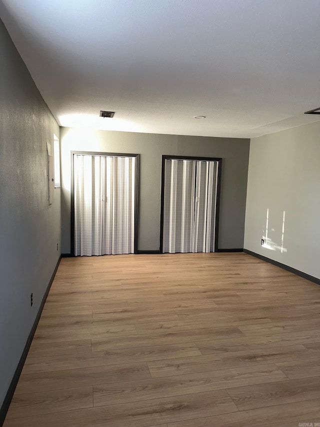 unfurnished room featuring visible vents, light wood-style flooring, and baseboards